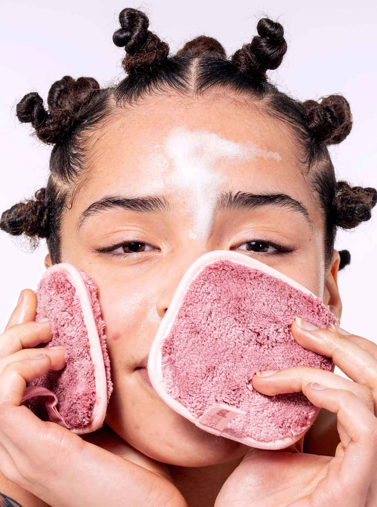 Model cleansing face with makeup remover pad